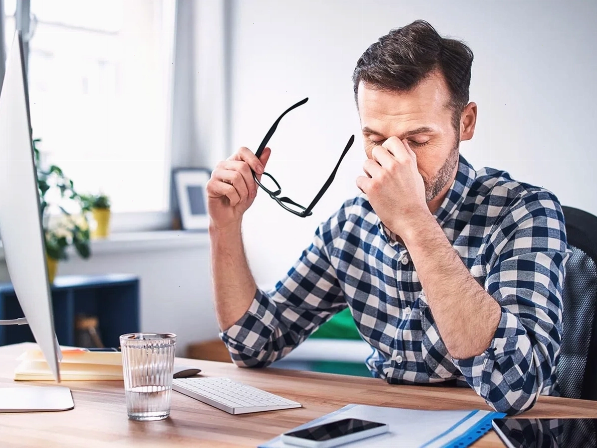 Nam giới đang làm việc với máy tính, có thể bị giật mắt do mỏi mắt